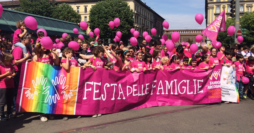 This article is about lesbian mothers obtaining legal status in Italy. In the photo, a group of people carrying a banner that reads "day of families" and holding pink balloons.