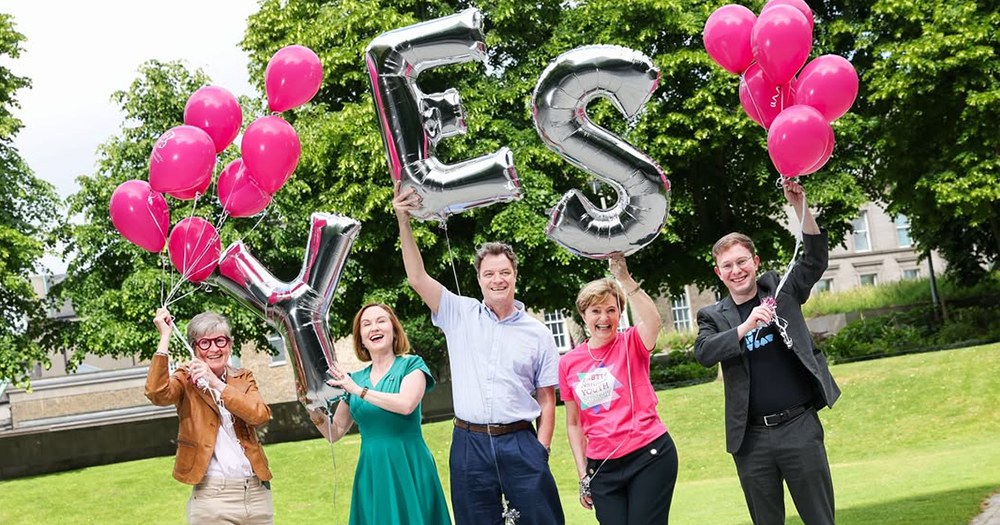 LGBTQ+ activists celebrating 10 years of Marriage Equality in Ireland, holding up baloons that read yes.