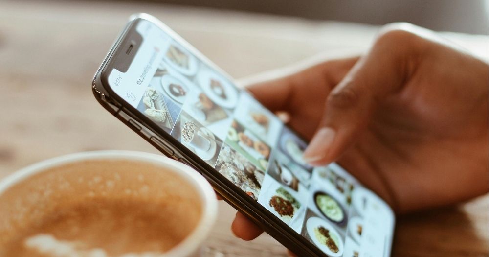 A hand holding a cell phone, resting on a table with a mug of coffee next to it for Appeals Centre Europe article