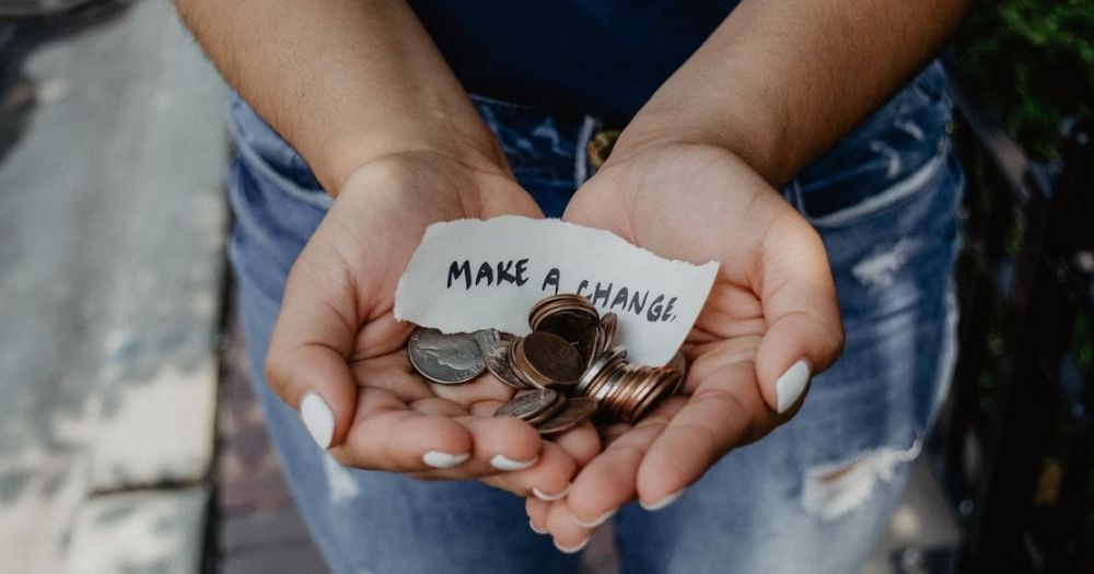 This article is about queer Irish charities. The images shows two hands holding change and a written note that reads "Make a change".