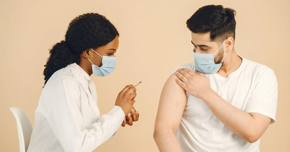 This article is about a vaccination programme rolled out in Northern Ireland. In the photo, a nurse holding a syringe as she's about to administer a vaccine to a man.