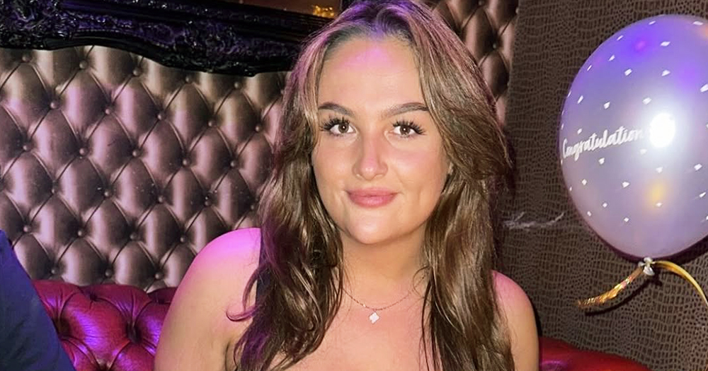 Photo of Paige Behan, a trans woman who was refused care at Dublin's St James’s Hospital, smiling at the camera while in a restaurant with a balloon.
