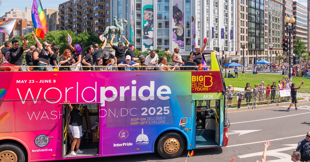 A WorldPride bus with people celebrating and waving Pride flags.