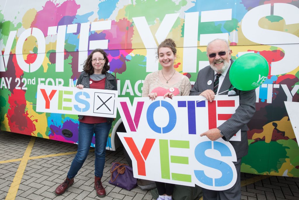 Photo by the National Library of Ireland with David Norris and two other activist holding a sign that reads "vote yes".