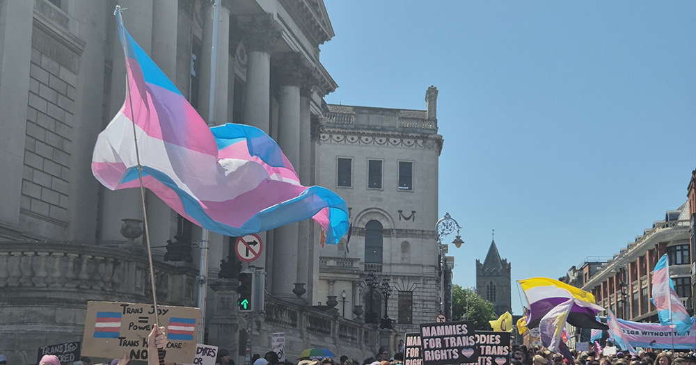 The article marks the 10-year anniversary of Ireland's Gender Recognition Act. The image shows a trans flag flying in Dublin.