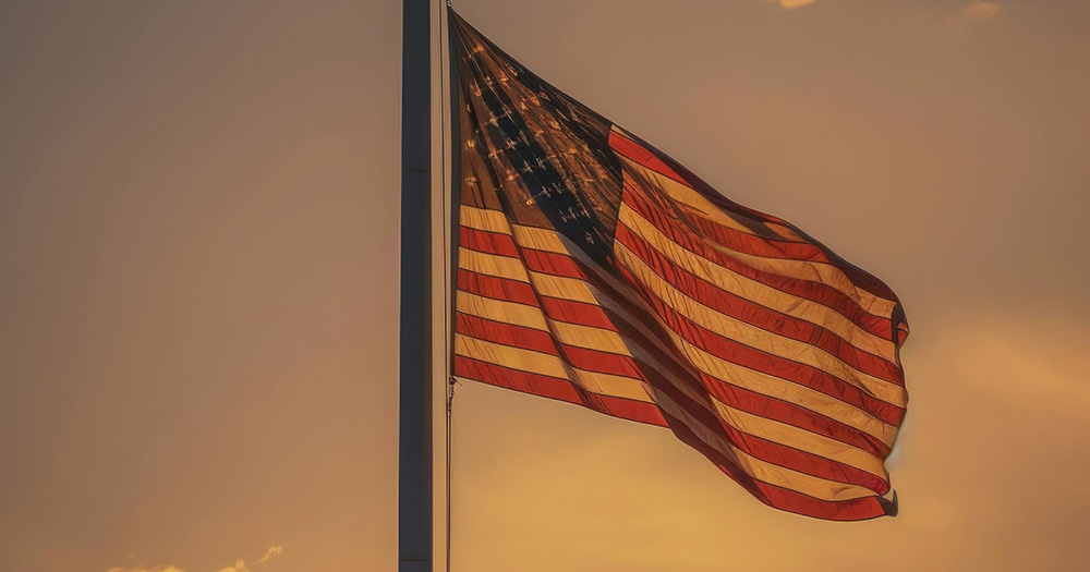 This article is about blue laws and anti-LGBTQ+ legislation in the US. The image shows a US flag at dusk.