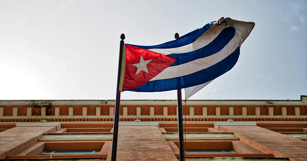 The Cuba flag flying off the side of a building.