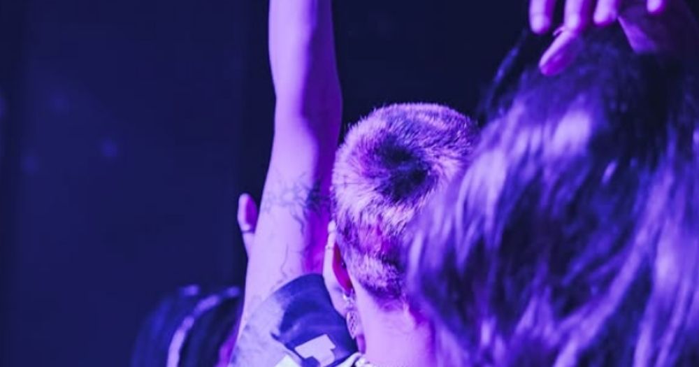 People in a dark, purple lit room enjoying a Dykon event, of which the founder is the same for Dykonic.
