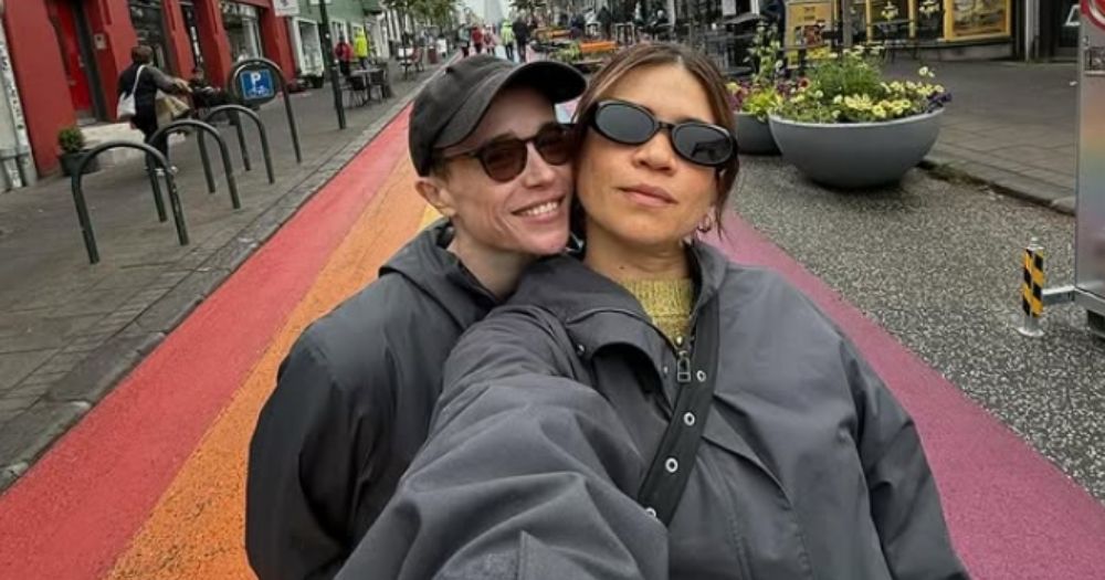 Elliot Page and Julia Shiplett posed together on a rainbow painted street.