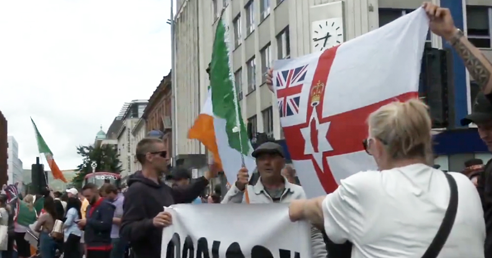 Irish anti-immigration protest with people holding Irish and loyalist flags.