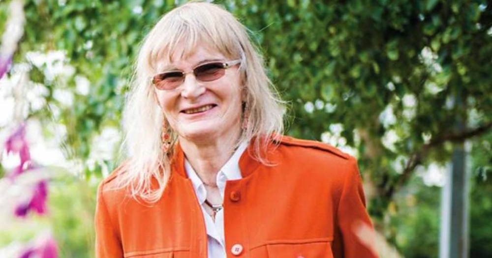 Dr Lydia Foy smiling at the camera while wearing an orange coat outdoors.