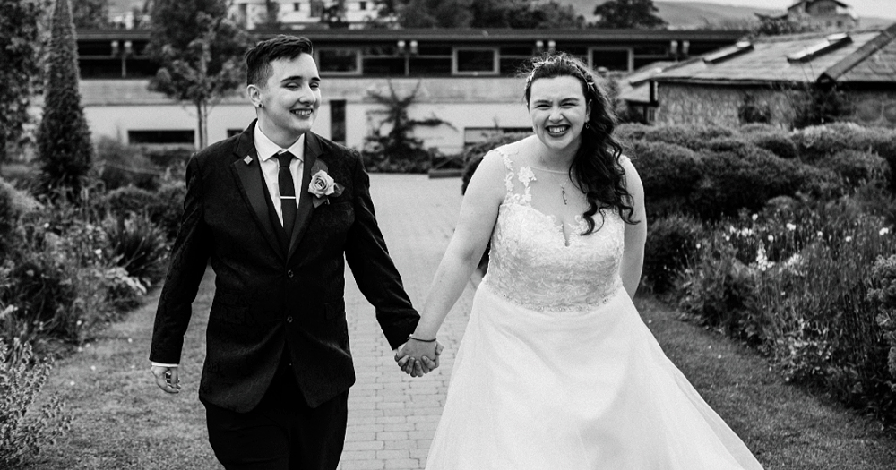 Photo of an LGBTQ+ couple who got married after the Marriage Referendum. In a black and white photo, they are walking and laughing while holding hands.