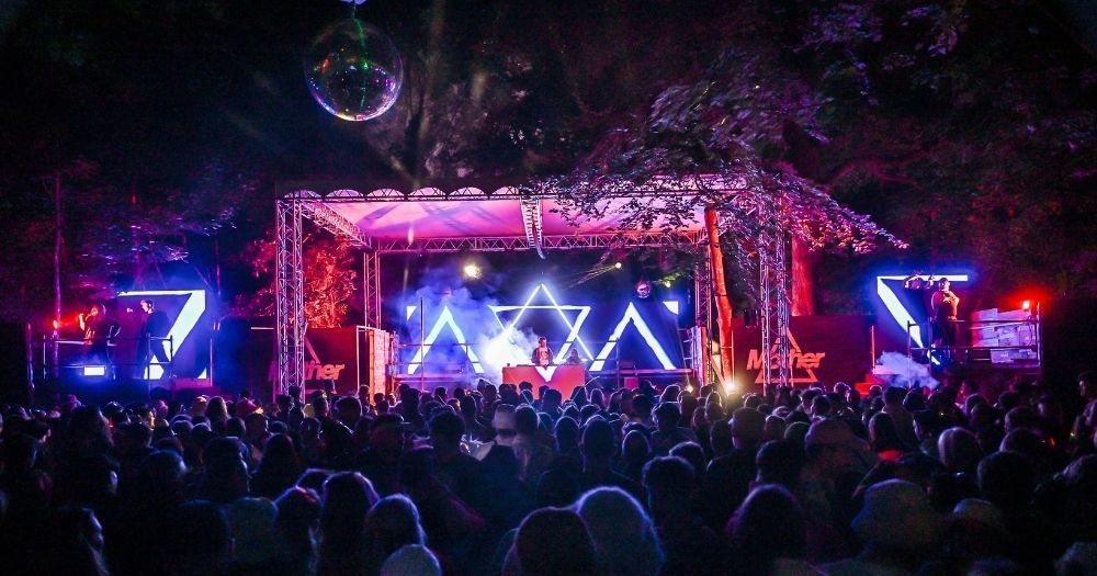 Mother party at Electric Picnic with blue and pink lights, with the crowd dancing in front of the stage.