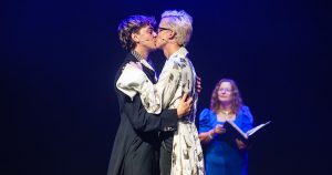 Joseph Martin and Linus Karp marry on stage at the Edinburgh Fringe. They kiss on stage as Jack Blackburn is seen holding a book in the background.