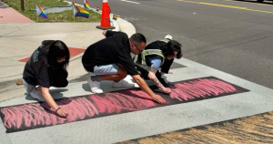 Image shows the community in Orlando re-painting the Pulse memorial rainbow crosswalk