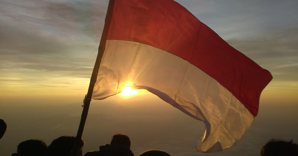An image of the Indonesia flag flying with the sun in the background.
