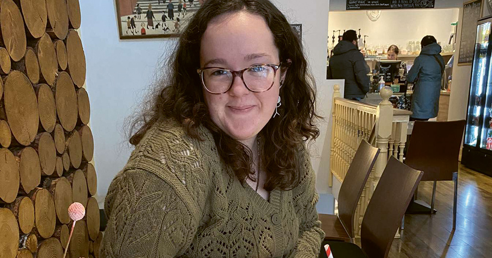 LGBTQ+ secondary school student Tara McCarthy sitting and smiling.