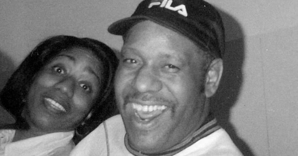 A black and white photograph of Ken Collier and Stacey Hale, black and queer pioneers of techno and house music. They are both smiling. Ken has a moustache and wears a Fila baseball cap. Stacey has a black bob haircut.