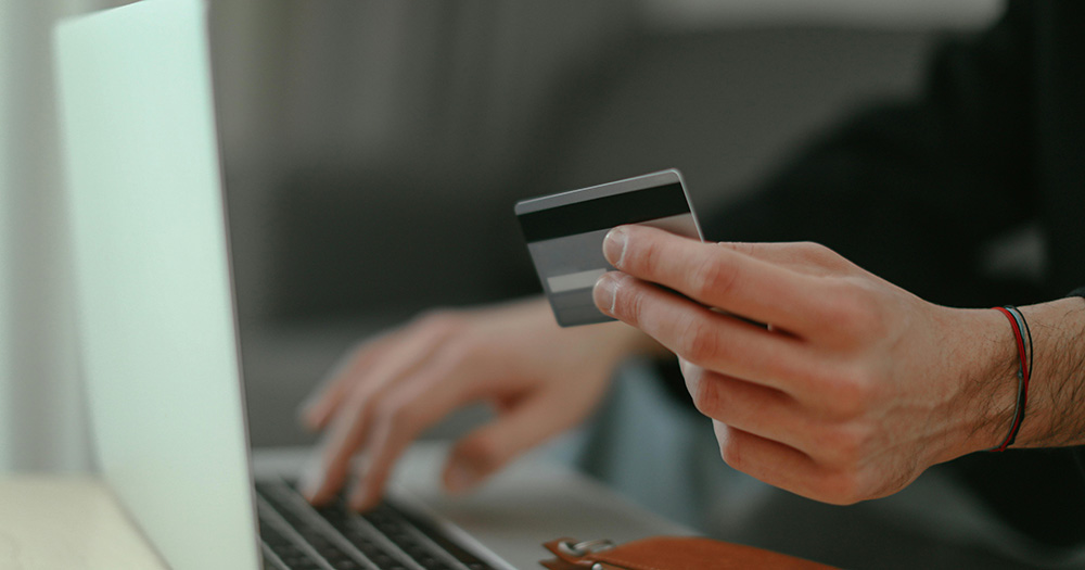 A person holding their card to pay for something on their laptop through Stripe.