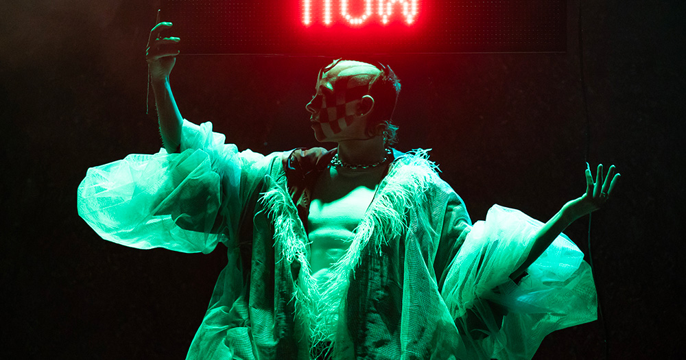 Drag artist Wet Mess under stage lighting performing TESTO.