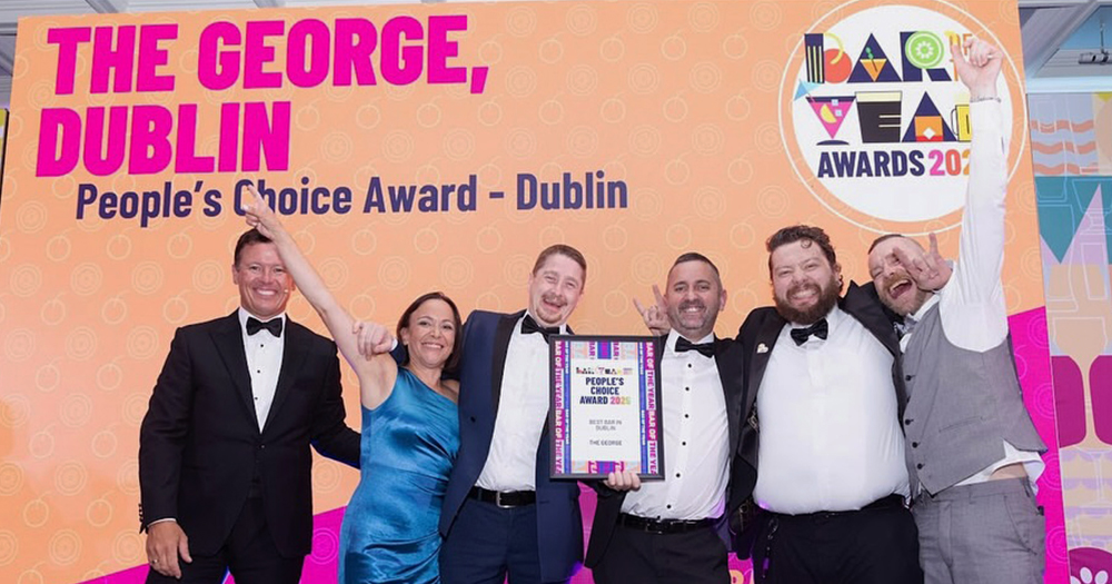 Staff members of the George receiving the Best Bar in Dublin by People's Choice Award on stage, with one of them holding the award and the others celebrating and hugging each other.