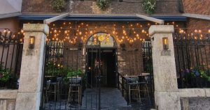 This article is about a garda accused of assaulting staff at a Dublin queer venue.In the photo, the entrance of Dublin's queer bar Pennylane with tables and fairy lights as decorations.