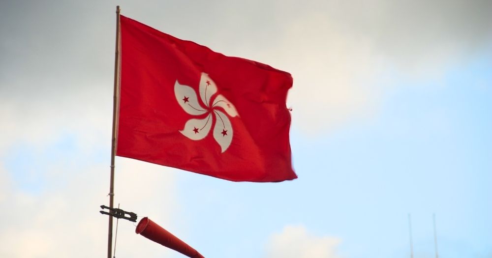 This article is about a bill for same-sex couples' rights being rejected in Hong Kong. In the photo, a Hong Kong flag, red with a white flower in the centre, flying in the sky.
