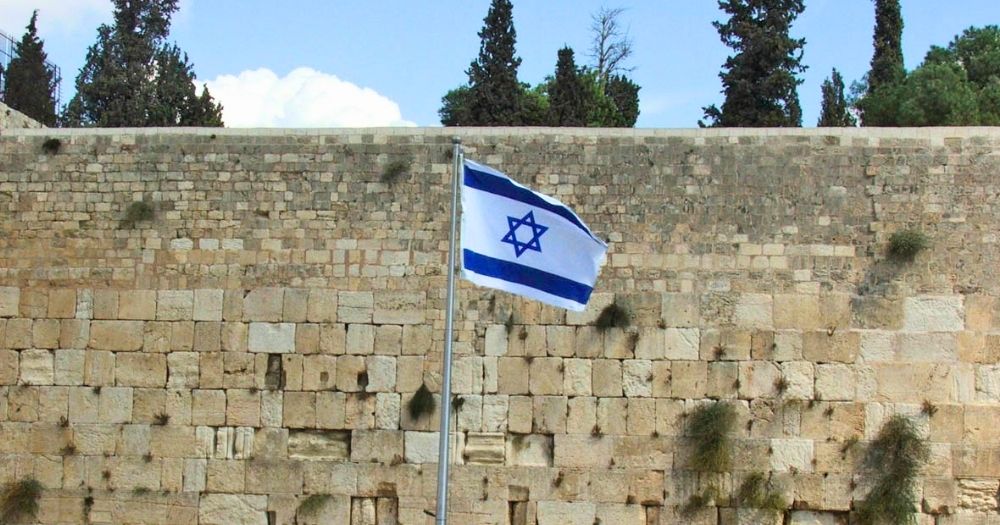 This article is about a Supreme Court ruling in Israel ordering the government to stop starving Palestinian prisoners. In the photo, an Israeli flag flying in front of a stone wall.