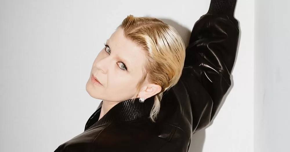 Swedish pop singer Robyn, who is rumoured to release a new album, looking at the camera while raising an arm. She's wearing a black jacket.