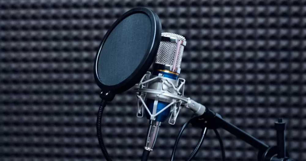 This article is about a Belfast LGBTQ+ radio. In the photo, a radio microphone in a dark insulated room.