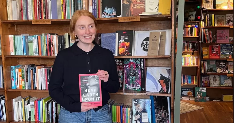 Chloe Michelle Howarth holding a copy of Heap Earth Upon It.