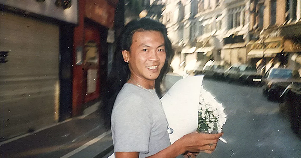 An image of Alfred Alphonso holding flowers in the middle of a street.