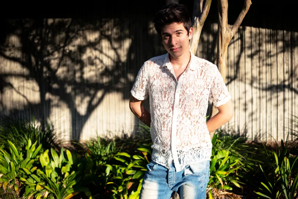 Dylan Rubic poses against a tree in a sunlit outdoor setting.