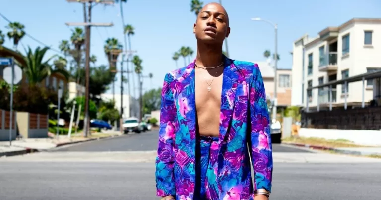Grey Cotton wears a multicoloured jacket that is open in the middle of a LA street.