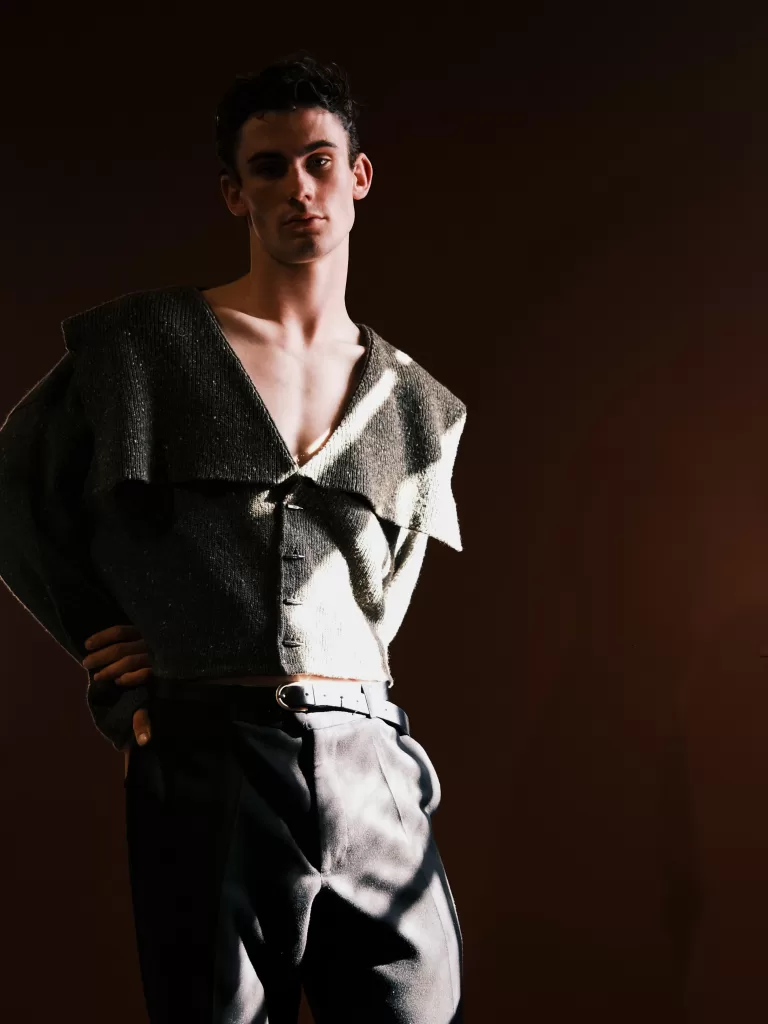 A model for Mar Knitwear's new collection with Donegal Yarns wears a woollen clothing item against a red backdrop.