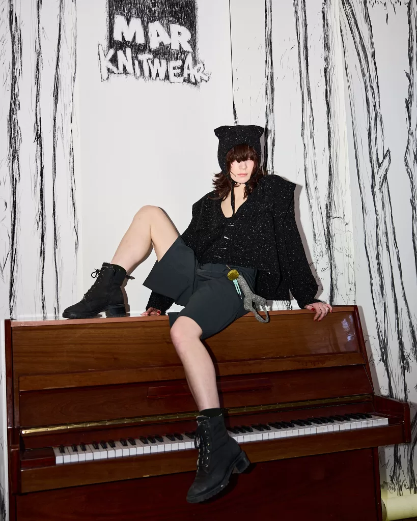 A model for Mar Knitwear's new collection with Donegal Yarns sits atop an upright piano.