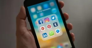 A person holds a phone, the screen is open on a tab of social apps.