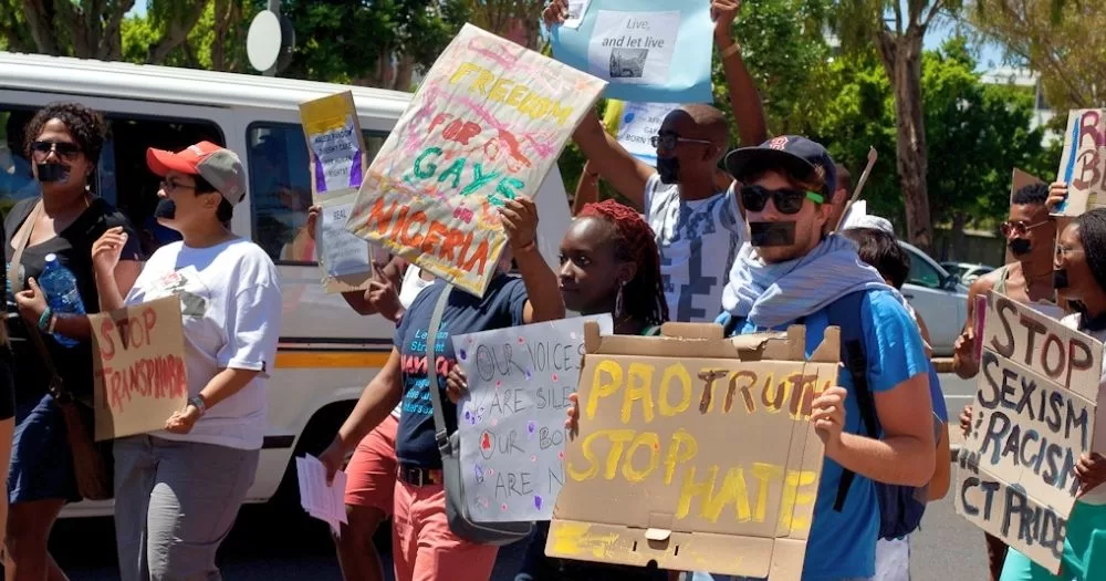 This article is about people being arrested at a gay wedding in Nigeria. In the photo, people protesting with signs with messages of support to the LGBTQ+ community.