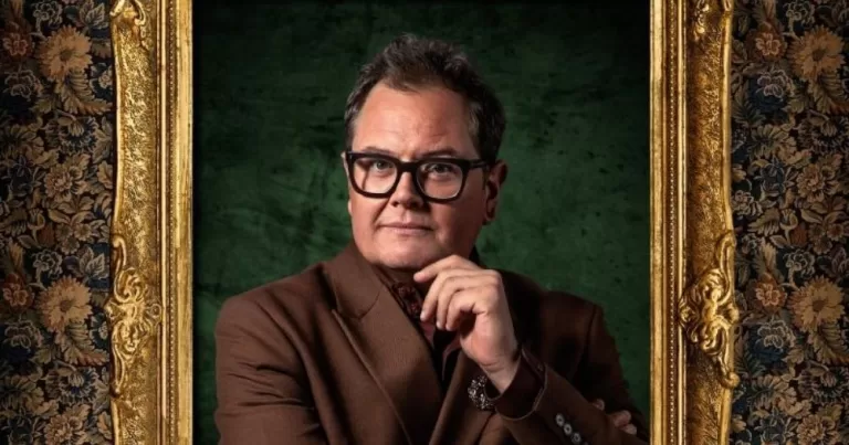 Alan Carr wins Celebrity Traitors. A portrait style picture of Alan Carr in a brown suit set against a green backdrop and in a golden frame.