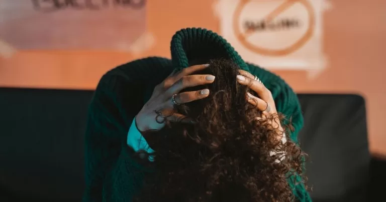 Image shows a young person holding his head in his hands. It is used to represent LGBTQ+ bullying.