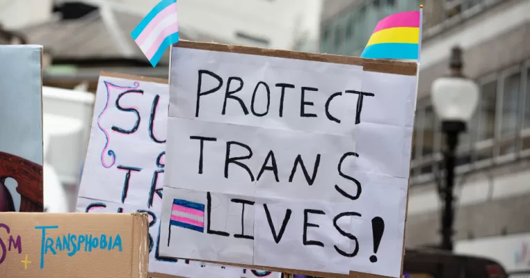 Image shows a protest sign that reads "Protect Trans Lives", Ofcom has dismissed more than 21,000 complaints regarding anti-trans comments made on Rupert Murdoch’s TalkTV