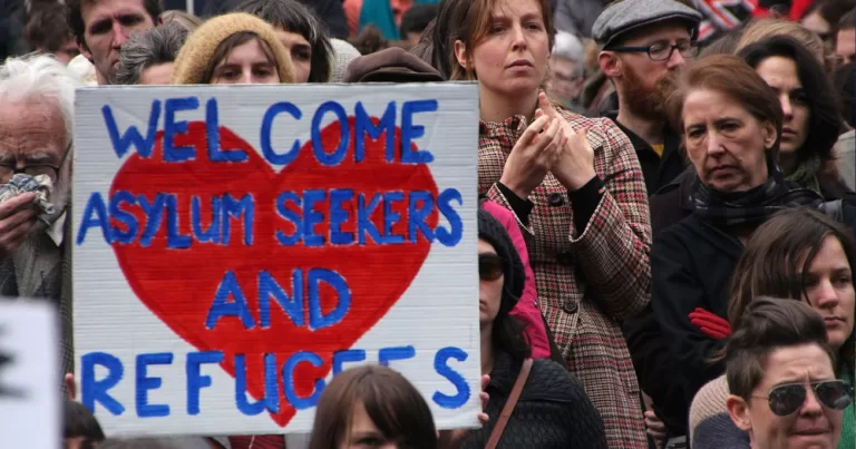 A person holds a sogn "Welcome Asylum Seekers and Refugees". This articel covers as arson attack on an IPAS.