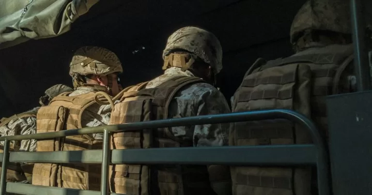 A group of military personnel in uniform sit in a truck. This image is being used to accompany an article about the US's trans military ban.