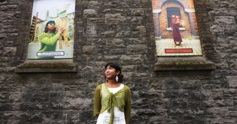 Image shows Venus Patel standing between two pieces of art in promotion for Dublin Gallery Weekend.