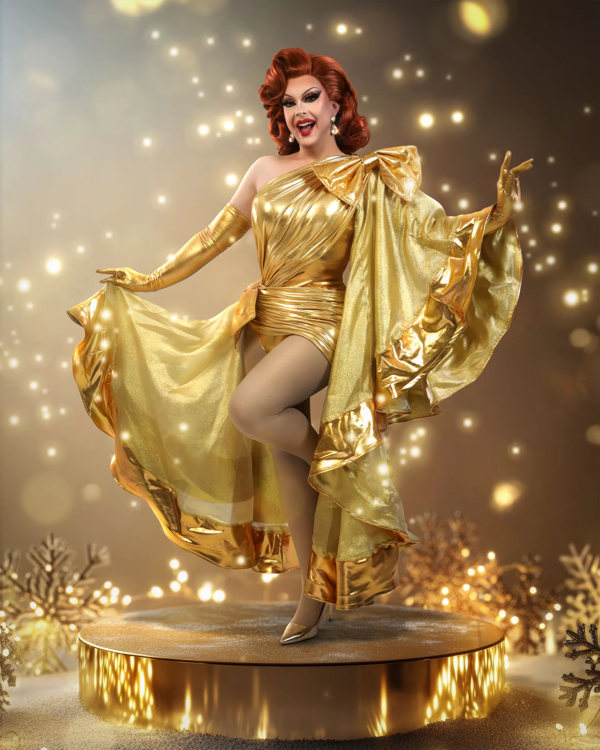 Bonnie Ann Clyde poses in gold in front of a glittering gold background.