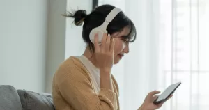 A person wearing headphones is listening to music. This article is in regard to creating a christmas playlist