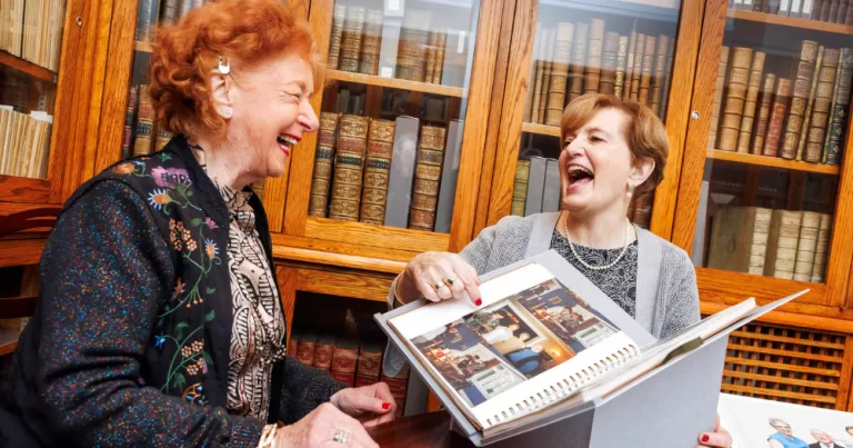 Katherine Zappone and Anne Louise Gilligan laughing together whilst holding their archival papers