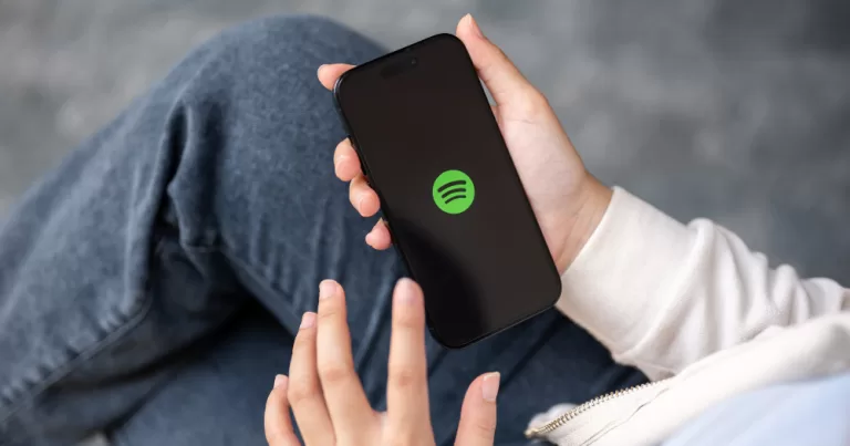 A person holding a phone displaying Spotify