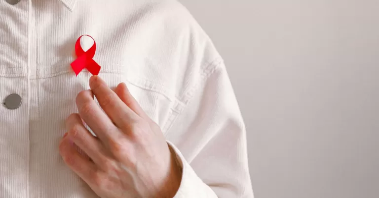 A person wearing a red ribbon in support of HIV and AIDS. The UK government has announced a major new HIV prevention and treatment programme
