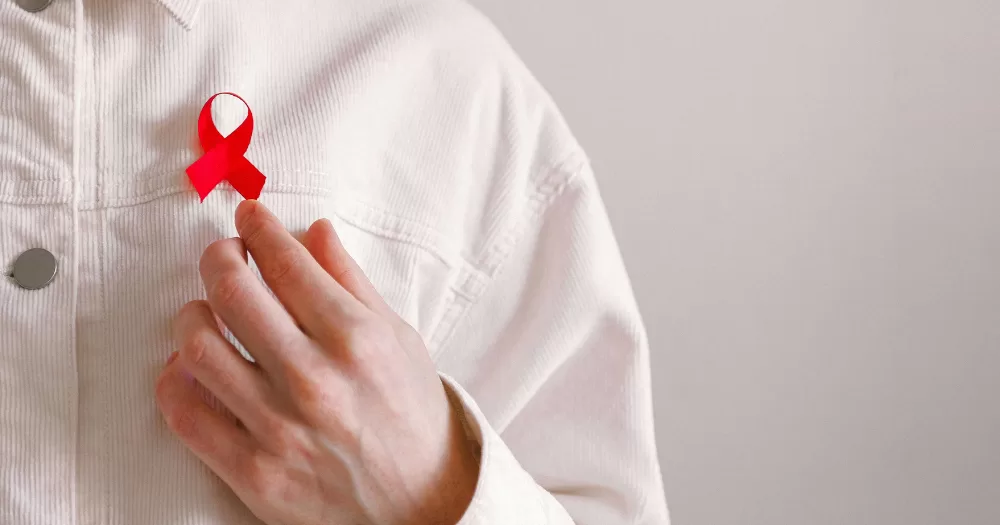 A person wearing a red ribbon in support of HIV and AIDS. The UK government has announced a major new HIV prevention and treatment programme